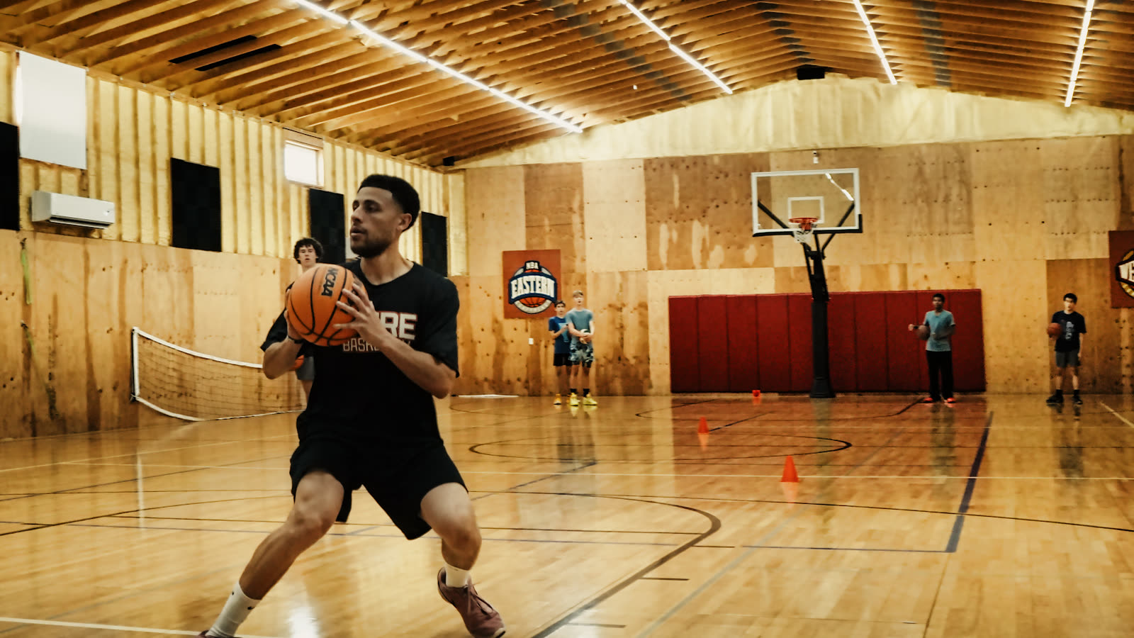 Coach Isaiah Easaw in a Pure Basketball shirt, ball on his hip, showing a move on the court