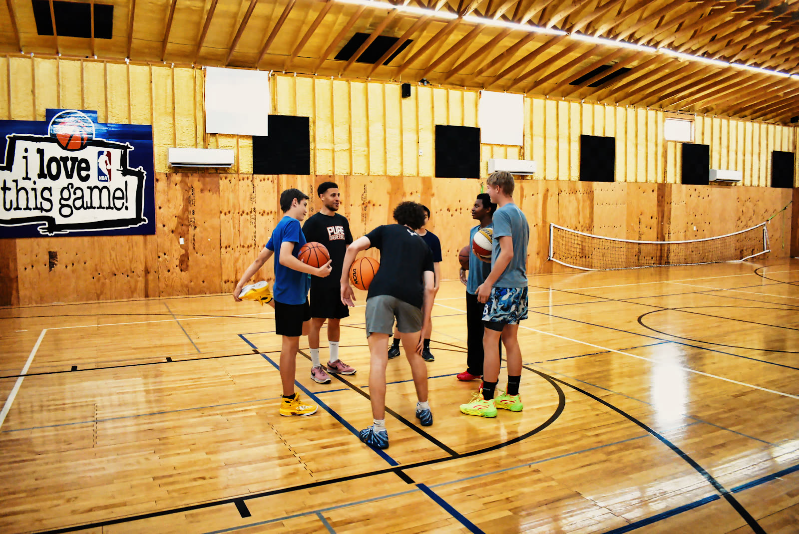Coach Isaiah talking with a small group of four players on the court